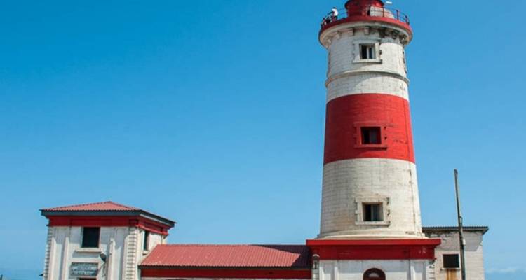 Phare rouge et blanc sous un ciel bleu.
