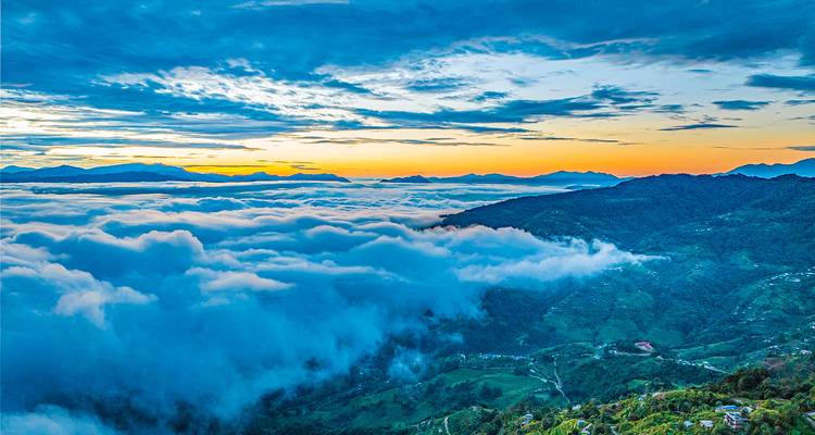 A breathtaking view of the clouds hovering over mountains during sunset