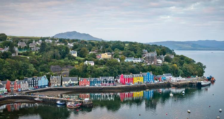 Un pueblo costero colorido con edificios de colores del arcoíris y un telón de fondo montañoso.