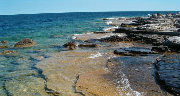 Aguas cristalinas y costa rocosa bajo un cielo azul.