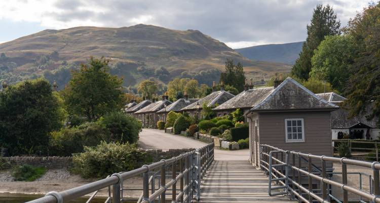Un sendero pintoresco del pueblo que lleva a pequeñas casitas con un fondo de colinas.