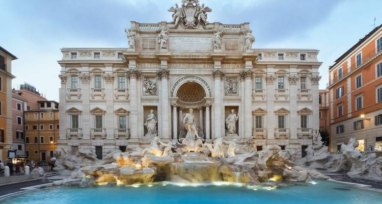 De Trevi-fontein in Rome, Italië, verlicht in de schemering met helder blauw water.