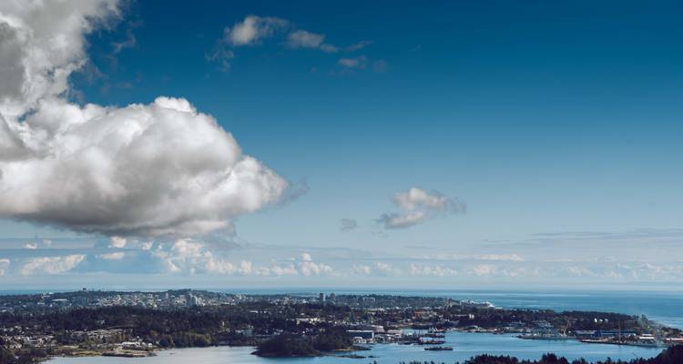 Panoramic view of a city near the water under a cloudy sky.