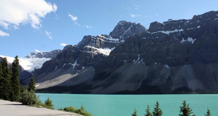 Montañas dramáticas junto a un lago turquesa bajo un cielo despejado.