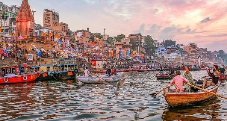 Busy riverfront with boats and historic buildings at sunset.