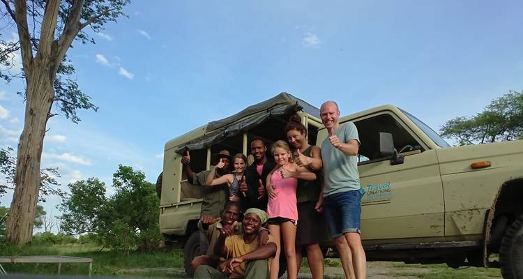 A happy group posing in front of a safari vehicle.