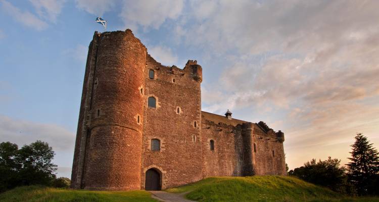 Castillo con una bandera en una colina al atardecer.