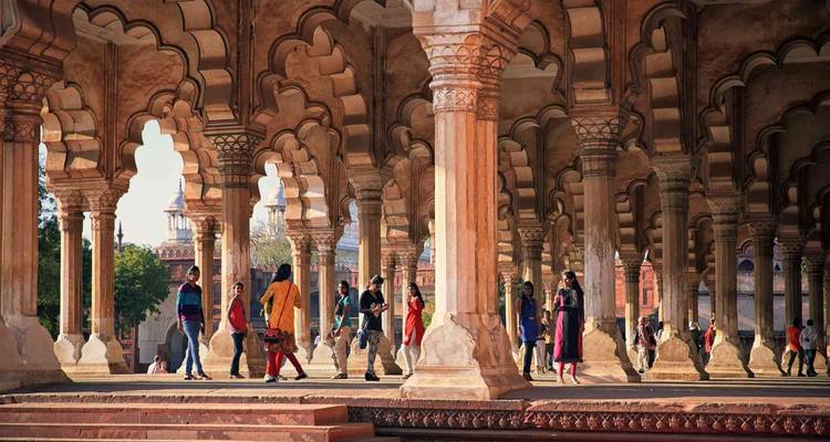Tourists explore the elegant arcade of scalloped arches as warm sunlight filters through the columns.