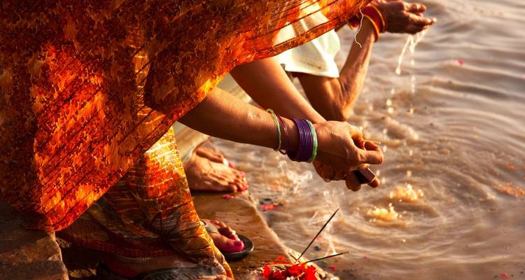 Mains de femmes effectuant un rituel au bord de la rivière.