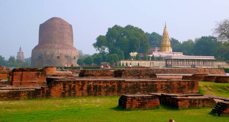 Ruines de brique avec un grand stupa et un temple en arrière-plan.