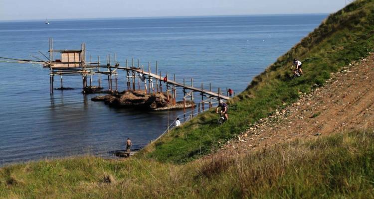 Fietsers op een kustpad naast een constructie die de zee in steekt