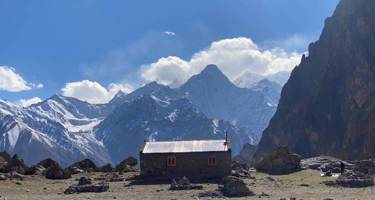 Een schilderachtig uitzicht van een klein huis met besneeuwde bergen op de achtergrond.