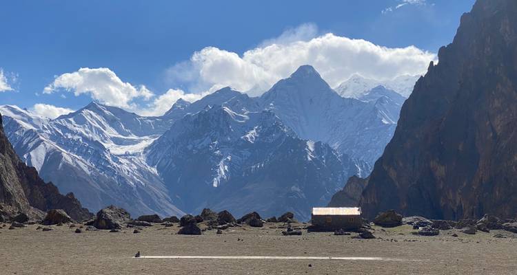 Een klein huis met op de achtergrond hoge besneeuwde bergen.