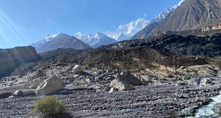 Een landschap met rotsachtig terrein and besneeuwde bergen in de verte.