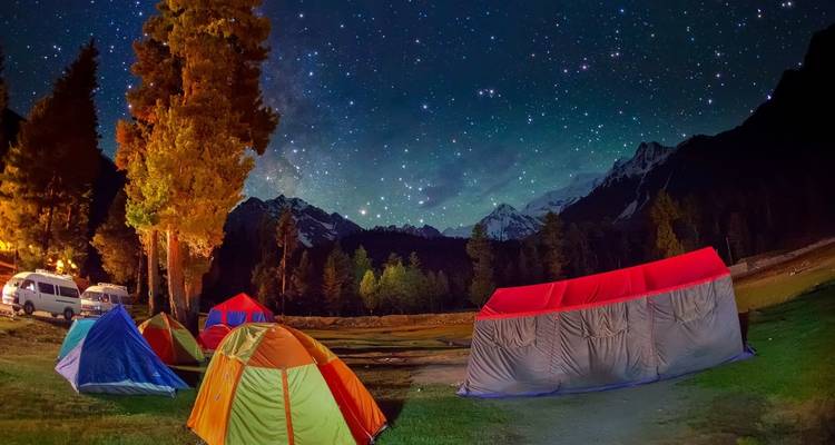 Acampar bajo un cielo estrellado con montañas.