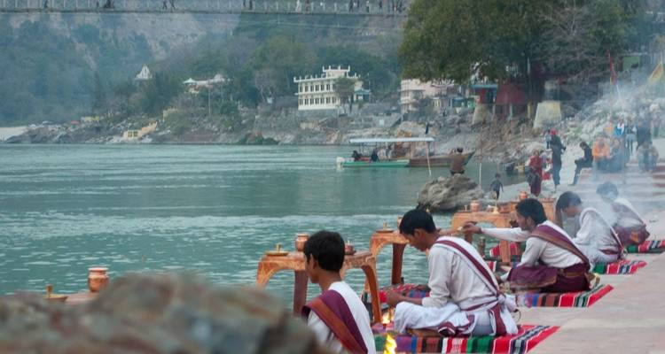 People conducting religious rituals by a riverside.