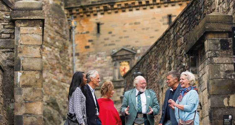 Eine Gruppe von Menschen, die vor einem historischen Steingebäude stehen und sich unterhalten.