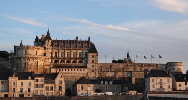 Château historique et bâtiments contre un ciel de coucher de soleil.