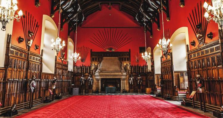 Intérieur d'une salle historique avec de hauts plafonds, de grands lustres et des décorations complexes.