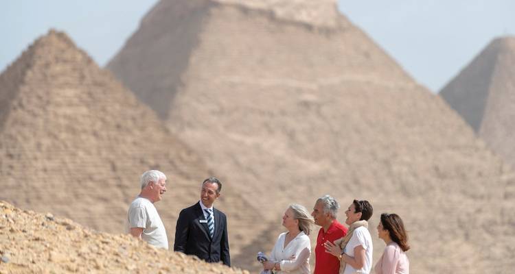 Gruppe von Menschen, die mit einem Führer vor den Pyramiden stehen.