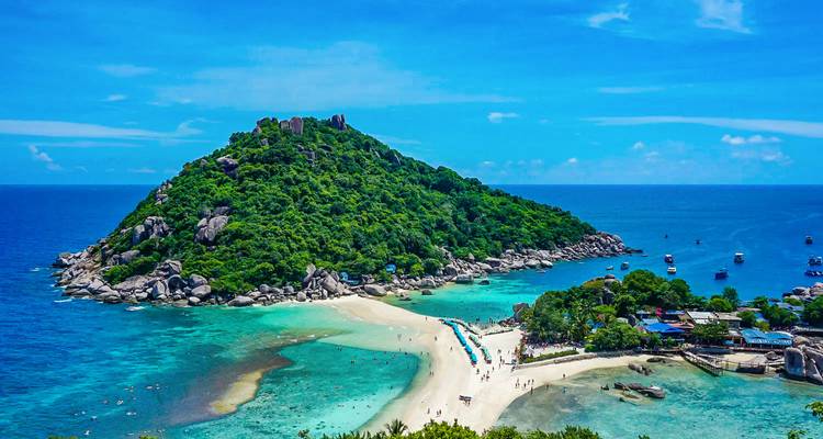 Lush green island surrounded by clear blue waters, connected by a sandbar.