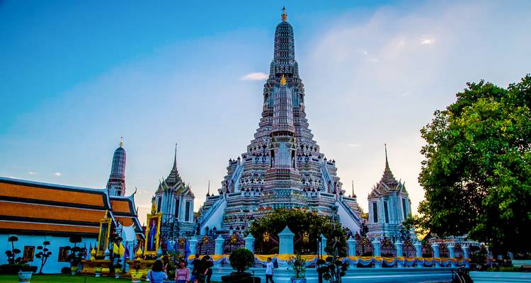 Grand ornate temple with a large central spire, lit by the dusky sky.