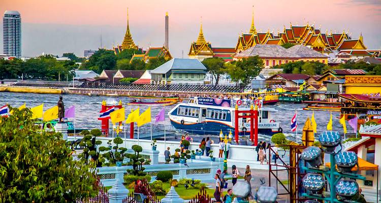 Scenic view of the Grand Palace area with a busy river during sunset.