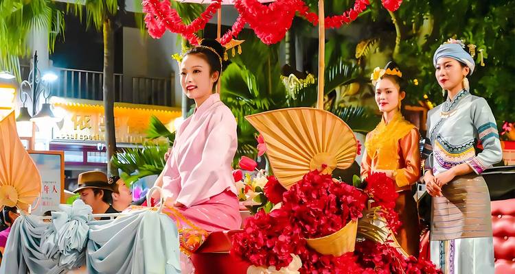 Women dressed in vibrant traditional attire during a night parade.