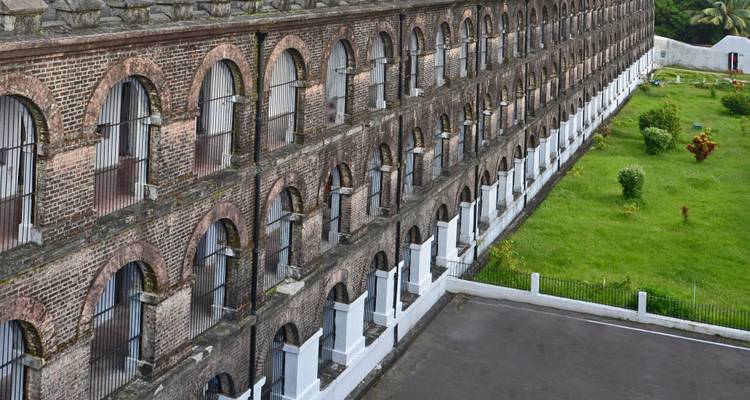 Grand bâtiment en brique avec de nombreuses fenêtres et une pelouse verte adjacente.