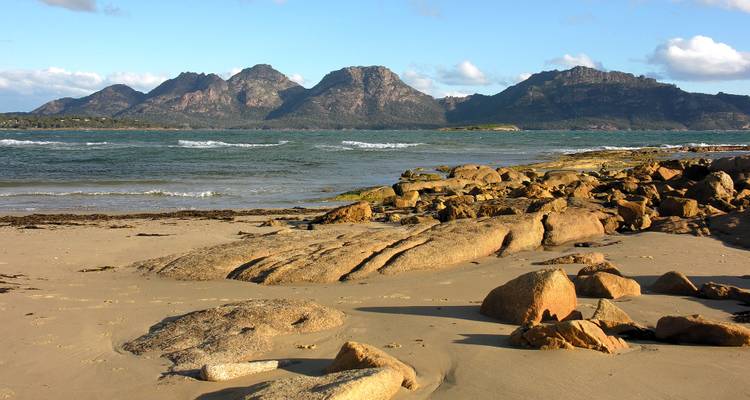 Plage rocheuse avec des montagnes en arrière-plan.
