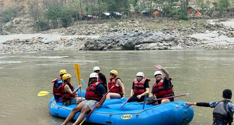 Groupe de personnes sur un radeau bleu dans une rivière, portant des casques et des gilets de sauvetage.