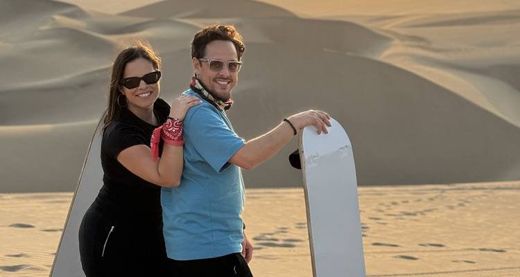 Pareja disfrutando del sandboarding en las dunas de arena.