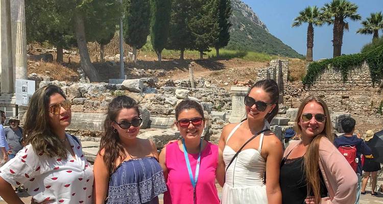 Group of women posing at ancient ruins site with trees.