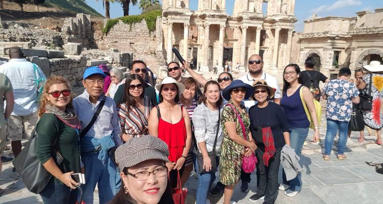 Large tour group posing in front of an ancient site with columns.