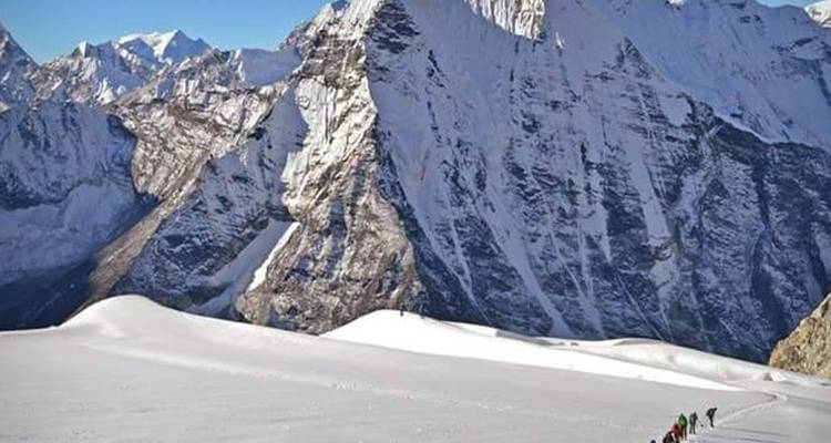 Besneeuwde berg met een rij trekkers.