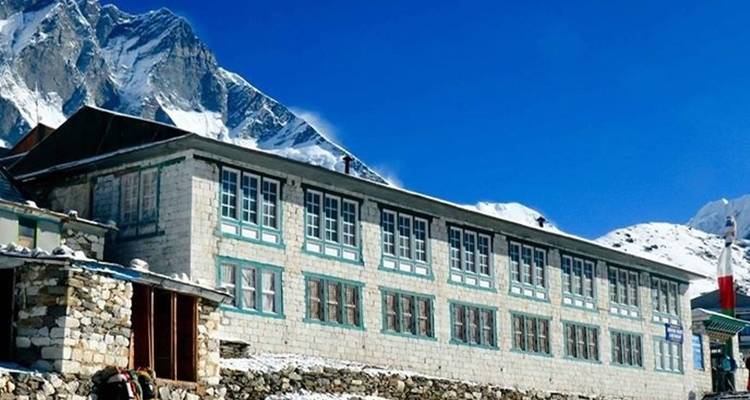 Berghut met besneeuwde toppen op de achtergrond.