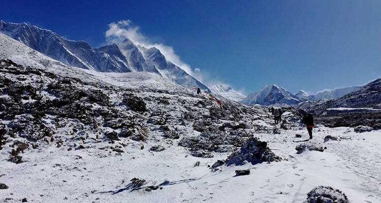 Berglandschap met sneeuwbedekte toppen en wandelende mensen.
