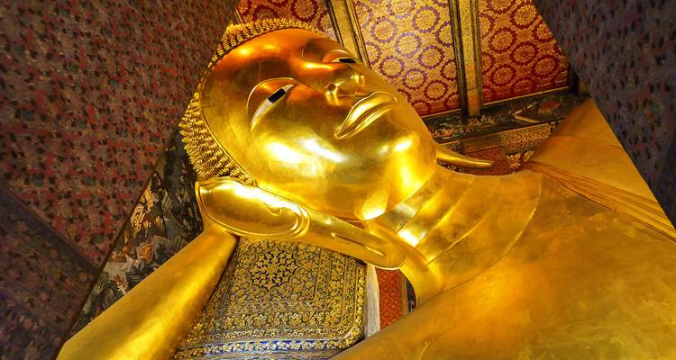 Estatua dorada de Buda reclinado dentro de un templo.