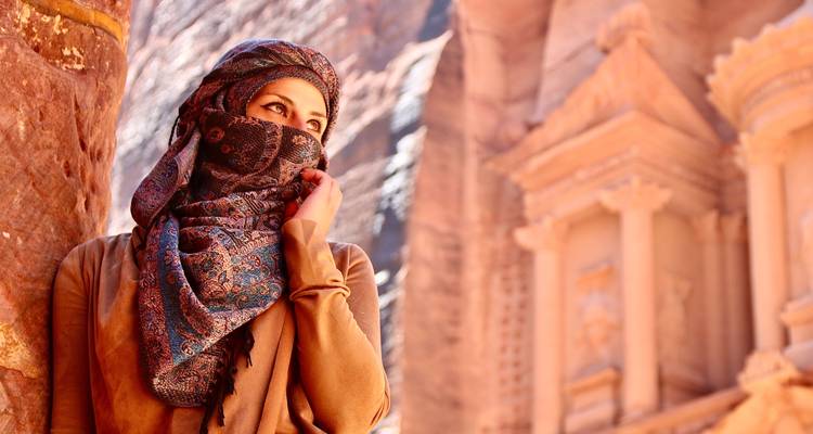 Person in traditioneller Kleidung mit Petra im Hintergrund.