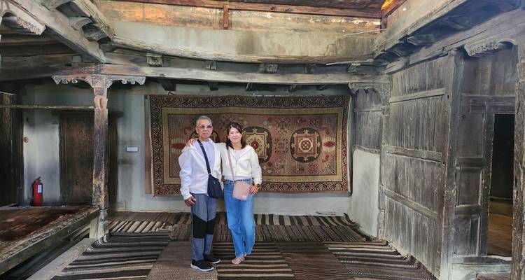 Dos personas de pie en un interior tradicional con alfombras y paredes de madera.