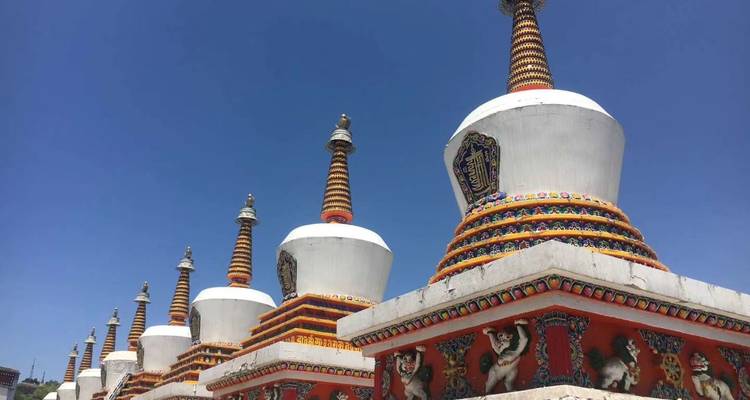 Fila de ruedas de oración coloridas o estupas bajo el cielo azul.