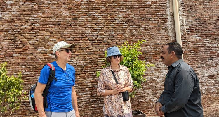 Toeristen die spreken met een lokale gids bij een historische muur.
