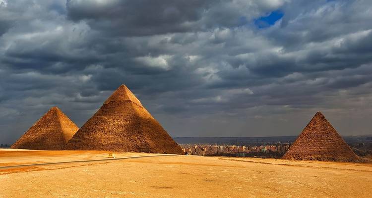 Three Pyramids of Giza with a dramatic sky.