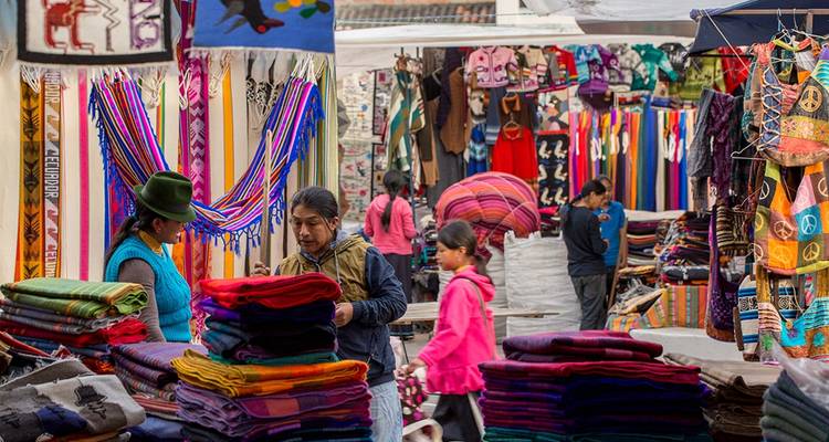 Marktkramen met kleurrijke textiel en lokale mensen die aan het winkelen zijn.