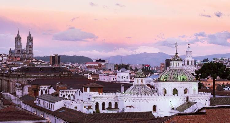 Een historisch stadsgezicht met gebouwen en bergen in de schemering.