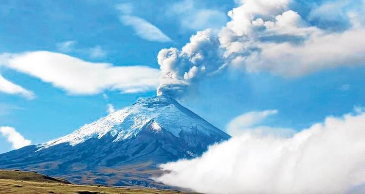 Actieve met sneeuw bedekte vulkaan met een rookpluim, tegen een levendige hemel.