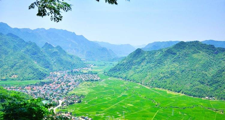 Uitzicht op een weelderige groene vallei omringd door bergen.
