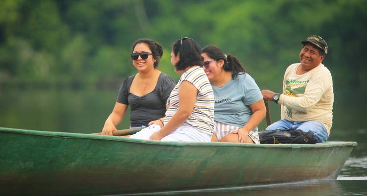 Groupe de personnes profitant d'une promenade en bateau sur une rivière calme entourée de verdure.