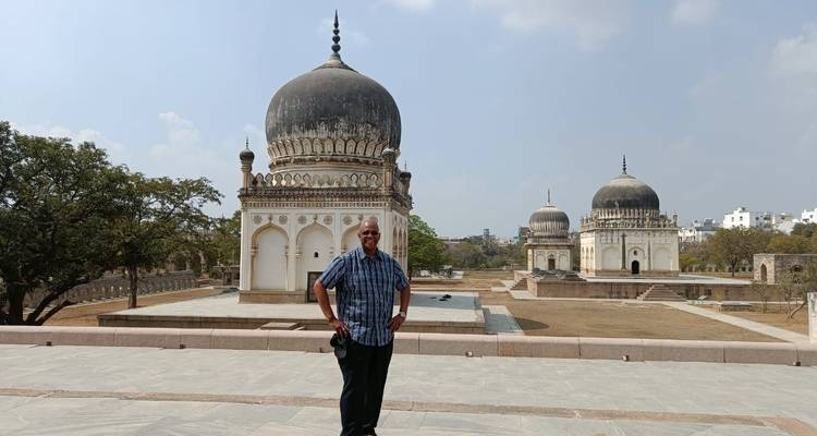 A man in front of historical buildings with domes.