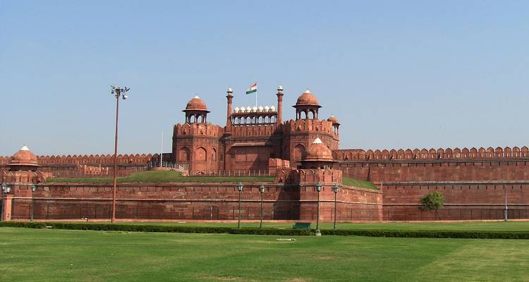 Historical red fort with a flag and green lawn
